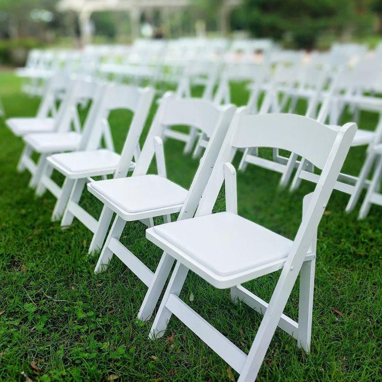 White Folding Wedding Chairs Arranged on Outdoor Grass